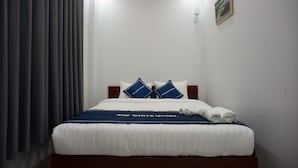 A hotel room with a neatly made bed, a blue and white bedspread, and a framed picture on the wall. - The White House (Ho Chi Minh City)