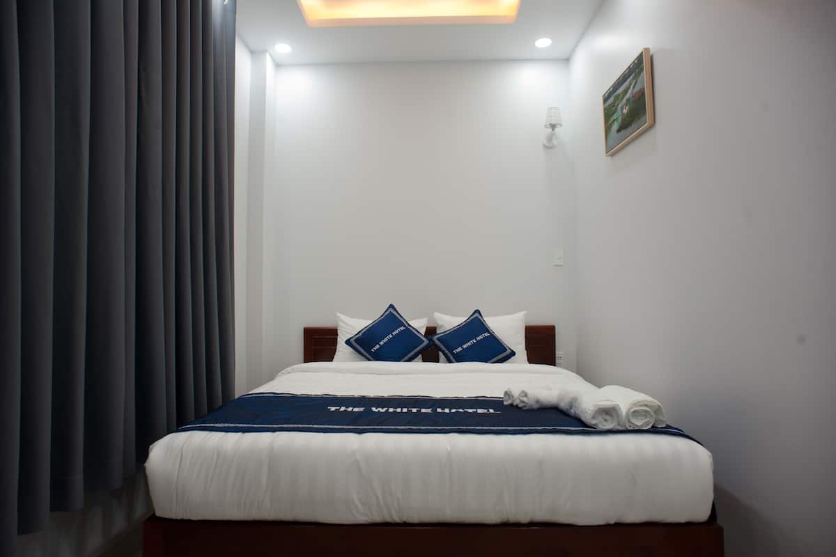 Une chambre d’hôtel avec un lit bien fait, une couvre-lit bleue et blanche, et un tableau encadré accroché au mur.