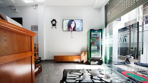 A reception area with a wooden desk, a bench, a television, and a refrigerator. - The White House (Ho Chi Minh City)