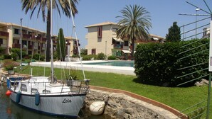 Un port de plaisance où est amarré un bateau appelé « Leia », une piscine et, au fond, des immeubles d’habitation.