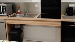 Eine kompakte Küche mit Mikrowelle, Toaster, Spüle und Kaffeemaschine.