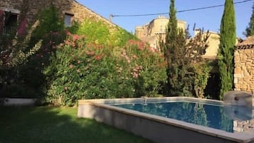 Una piscina al aire libre, sombrillas, sillones reclinables de piscina