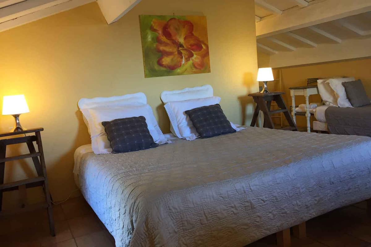 Una camera da letto con un letto grande, due comodini con lampade, un quadro al muro e una scala.