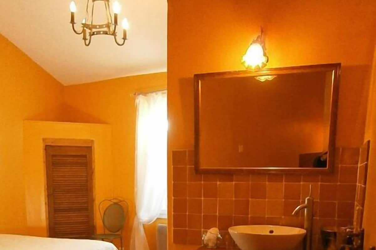 Una camera d'albergo con un letto, un bagno con un lavandino e asciugamani sul pavimento.