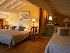 A cozy bedroom with two beds, a wooden ladder, a small stool, and a kitchen area with a sink and cabinets. - Les Aiguières en Provence (Suze-la-Rousse)