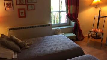 A hotel room with two beds, a window with curtains, a floor lamp, and framed pictures on the wall.