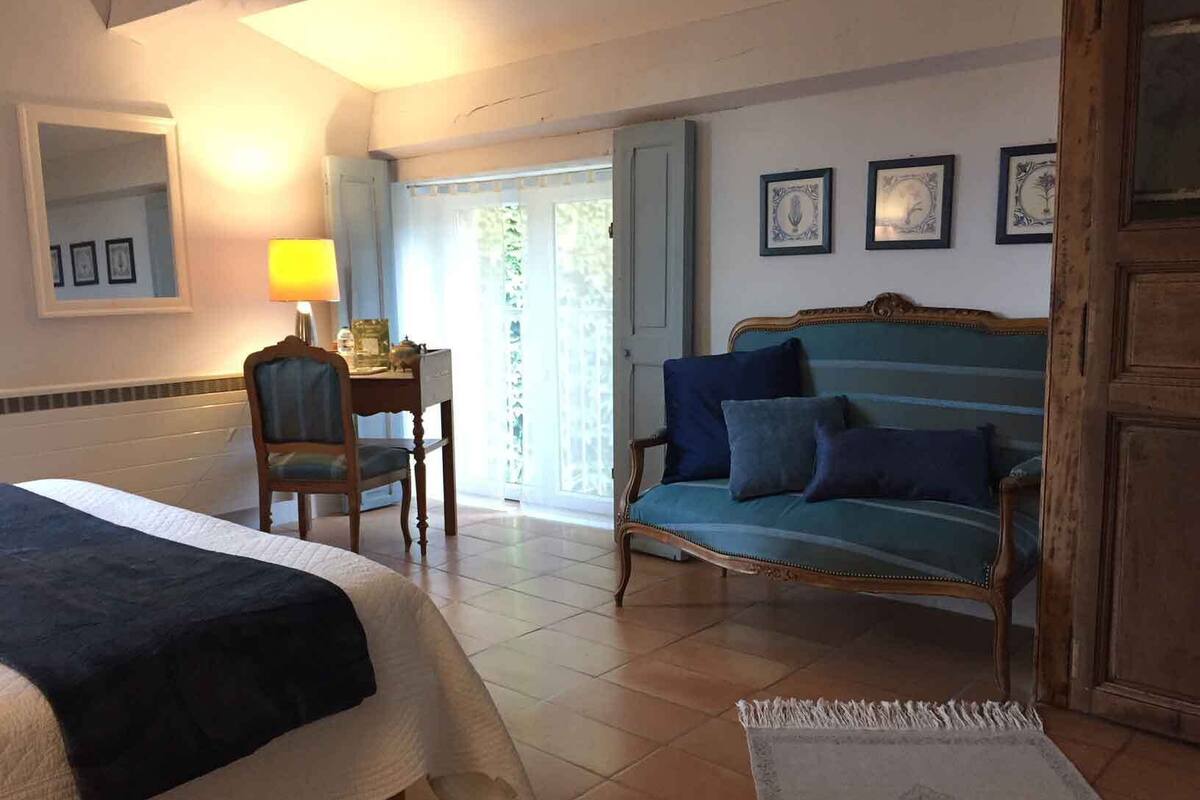 Una camera d'albergo con un letto, una scrivania, una sedia, un divano e una porta.