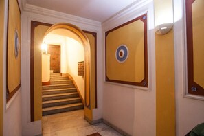 A hallway with a staircase, a door at the end, and a wall with a circular emblem. - Casa Zeffiro, two minutes walk from Trevi Fountain (Roma)