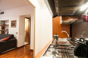 A compact kitchen with a gas stove, a sink, and a wooden countertop.