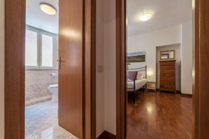 A bedroom with a bed, a dresser, a nightstand, and a window.