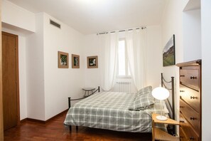 A bedroom with a bed, a bedside table with a lamp, a dresser, and three framed pictures on the wall. - Casa Zeffiro, two minutes walk from Trevi Fountain (Roma)
