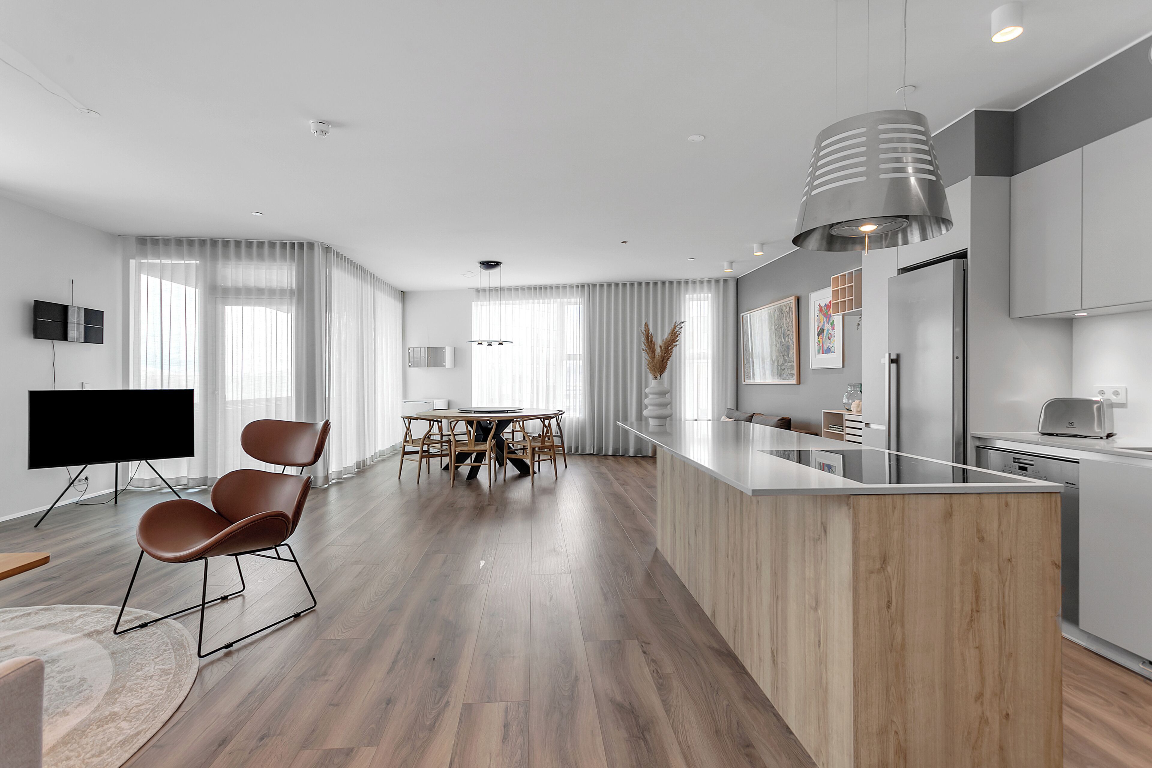 A modern kitchen with a wooden island, stainless steel appliances, and a dining area with a table and chairs.