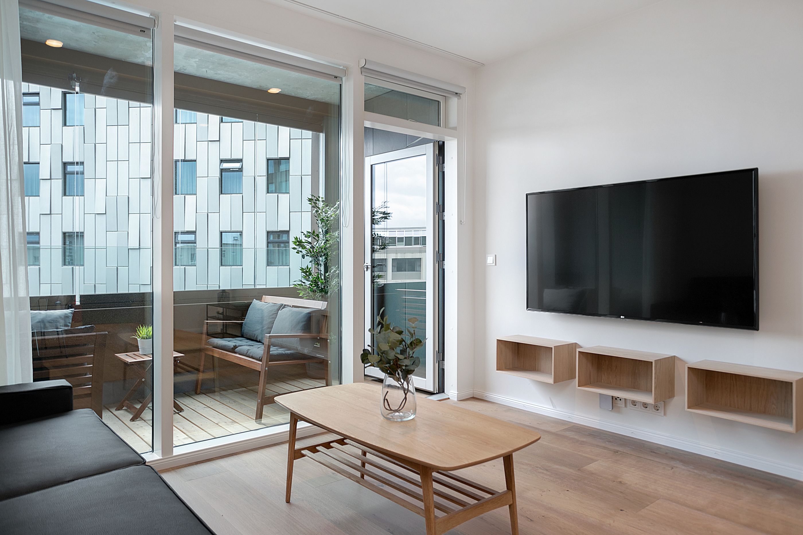 Un soggiorno moderno con una grande TV, un tavolo in legno e un divano.