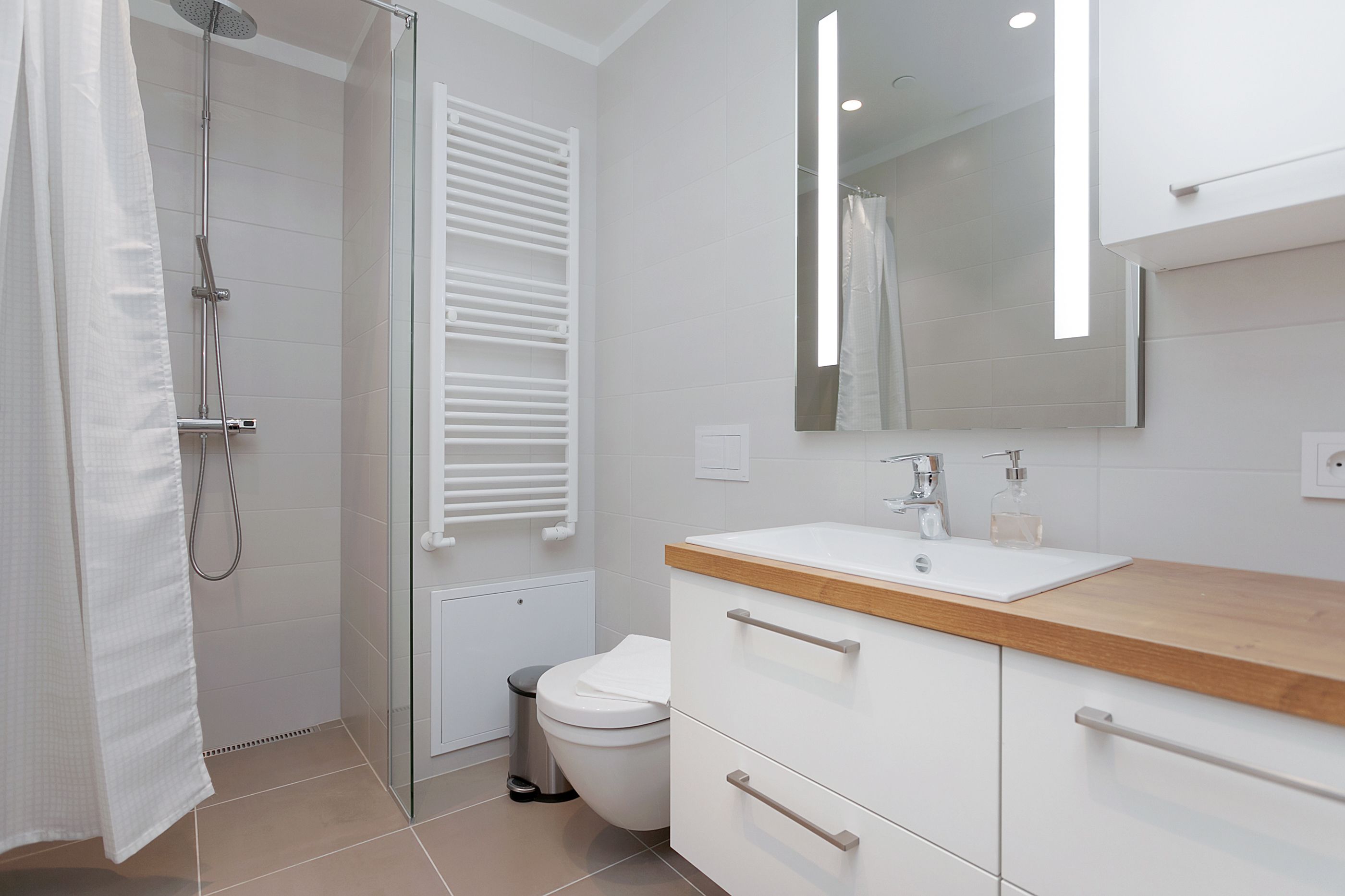 A modern bathroom with a shower, toilet, and vanity with a mirror.