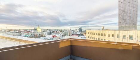 Uma varanda com vista para um horizonte urbano, incluindo um edifício alto com a placa 'FOSSIL'.