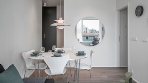 A modern dining area with a round mirror, white chairs, and a white table set for four. - Sif Apartments by Heimaleiga (Reykjavik)