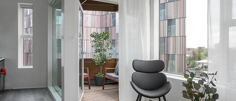 A modern interior with a dining area, a large window with curtains, and a view of a building outside.