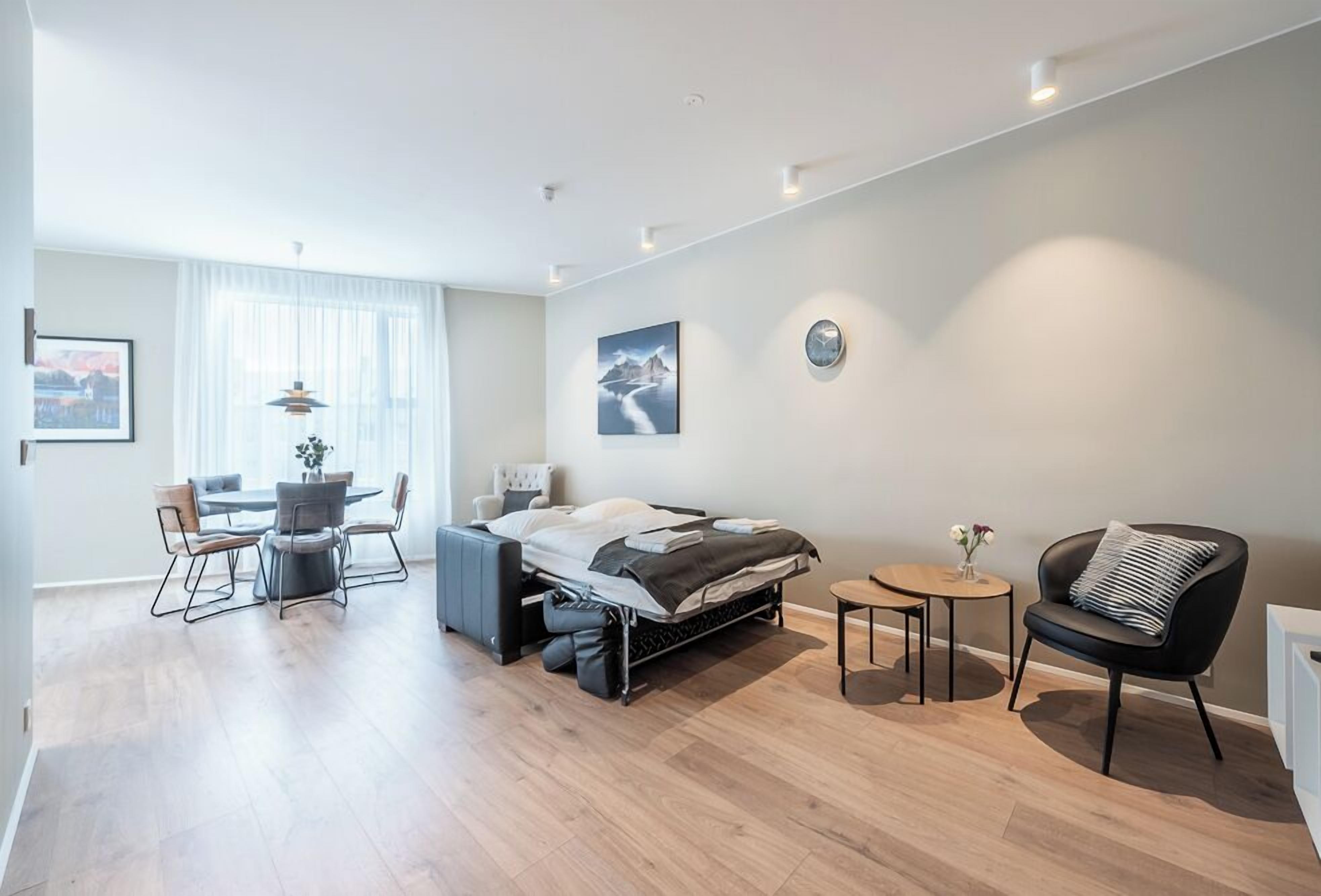 Une chambre d’hôtel moderne comprenant un lit, un coin repas et un petit coin salon.