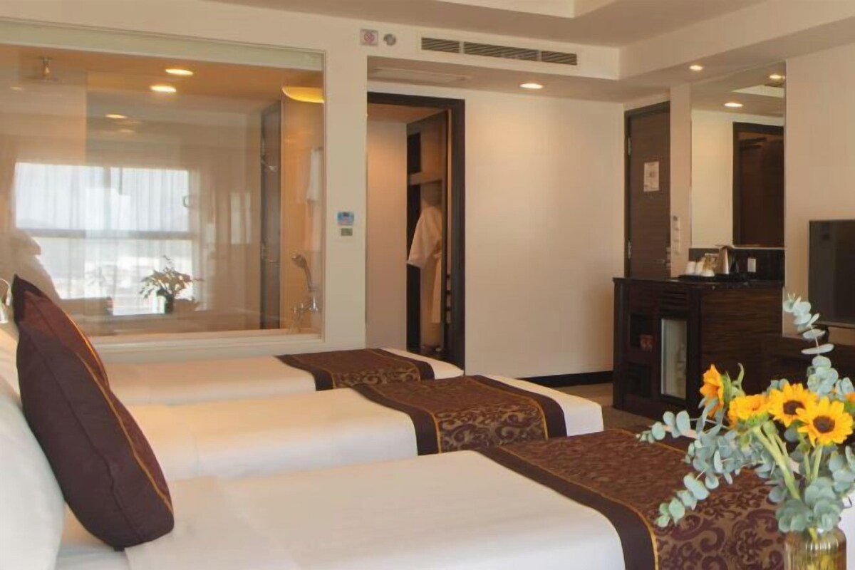 Una habitación de hotel con dos camas, televisión, escritorio y ventana con cortinas.