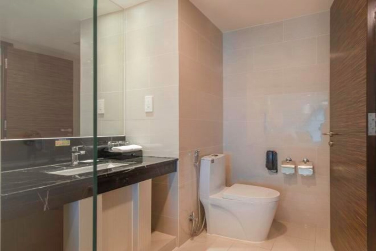 Une salle de bain moderne avec une douche à parois de verre, des toilettes blanches et un plan de toilette noir avec un lavabo.