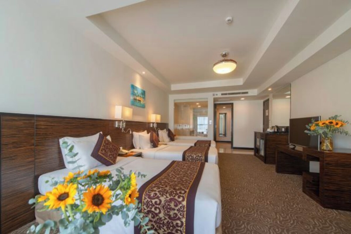 A hotel room with two beds, a desk, and a TV.