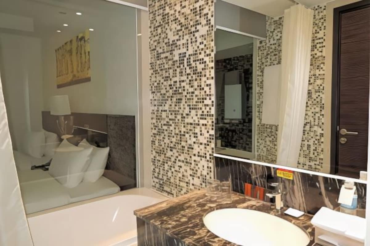 Une salle de bain moderne avec un grand miroir, un lavabo en marbre et une douche à parois de verre.