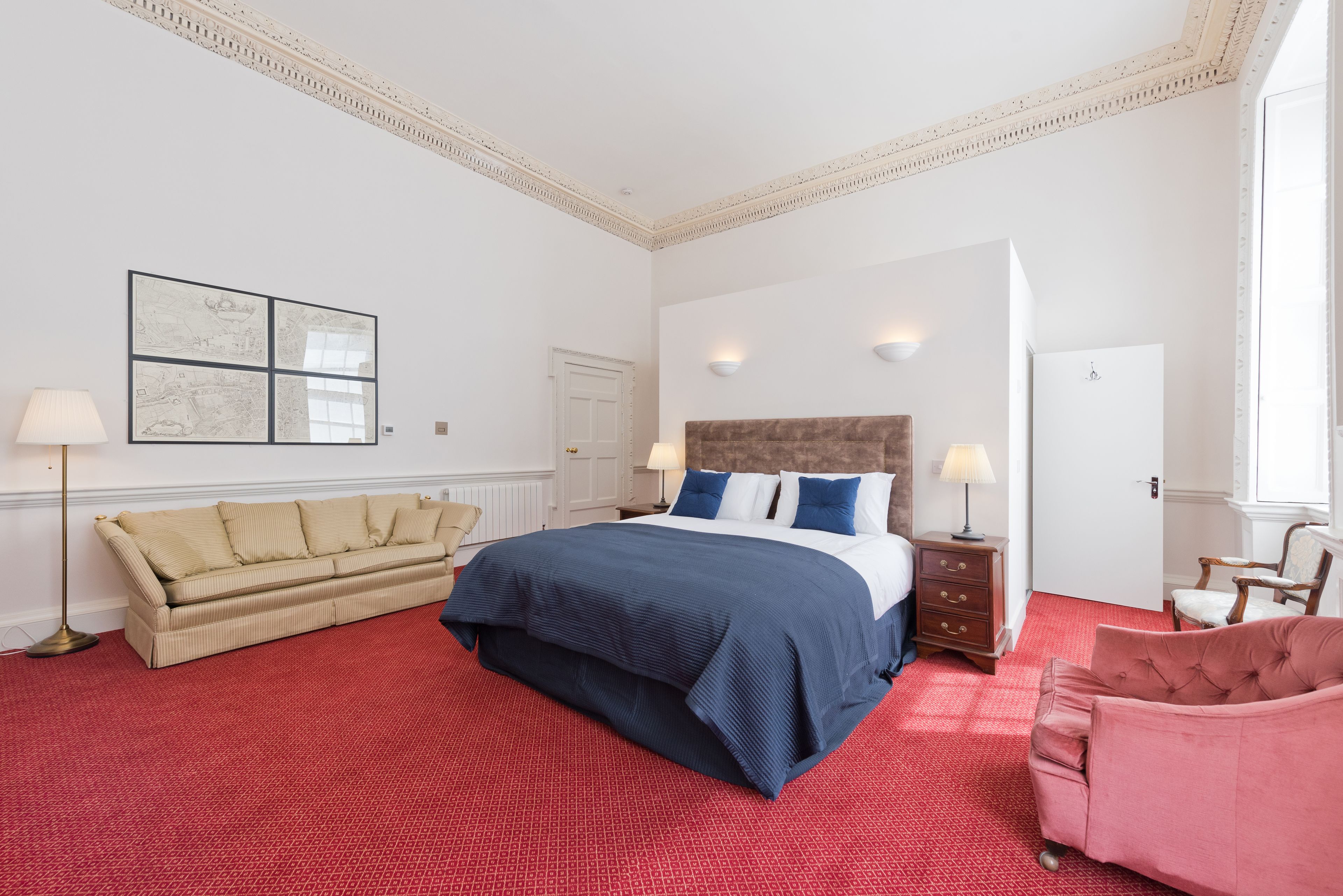 Une chambre à coucher avec un grand lit, un canapé, un fauteuil et une table de chevet.