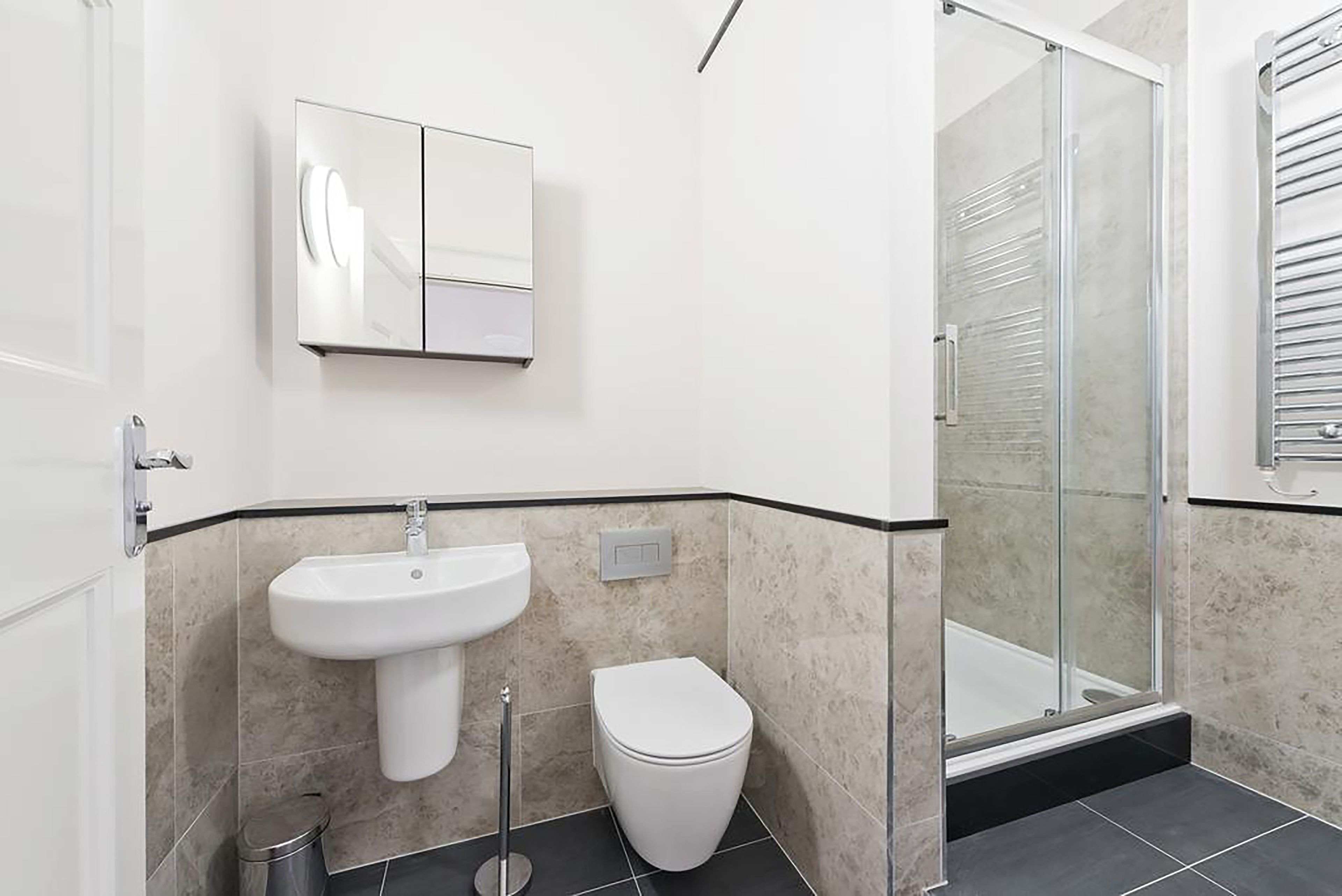 Ein modernes Badezimmer mit einem Waschbecken auf Säule, einer Toilette und einer Duschkabine aus Glas.