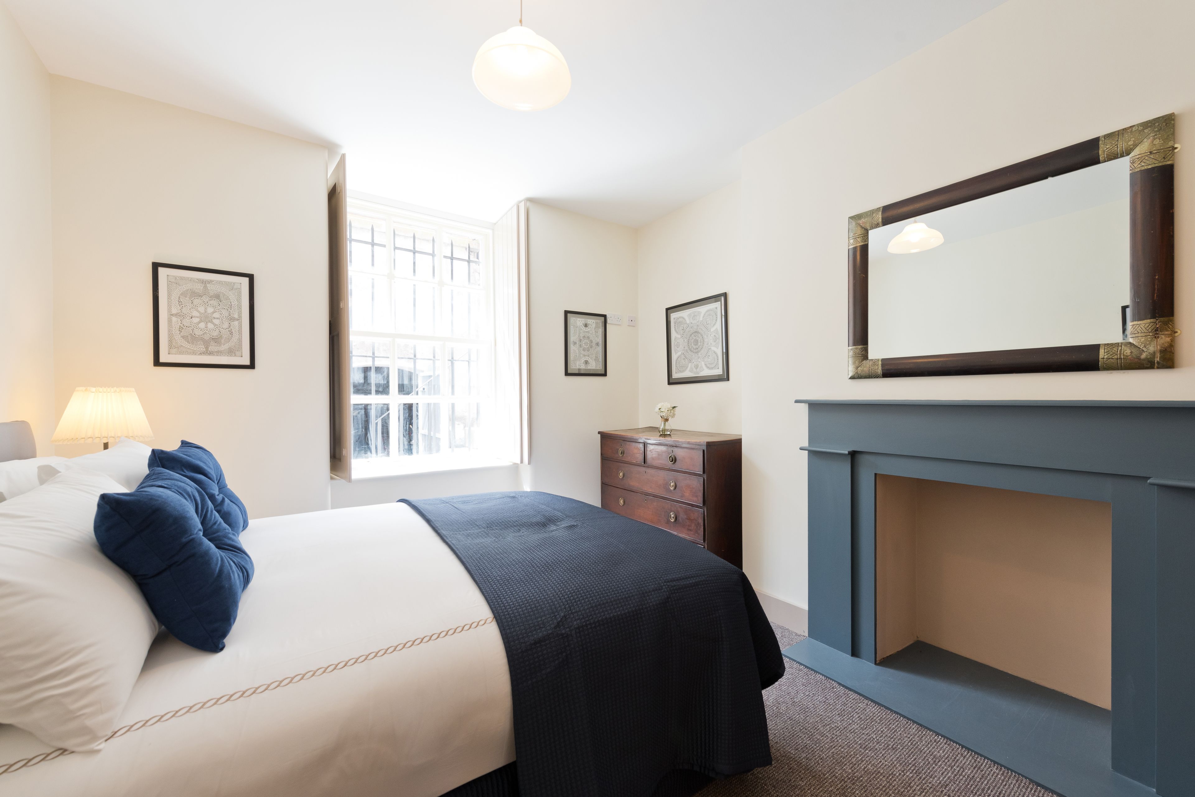 Quarto de hotel com cama, cômoda e lareira.