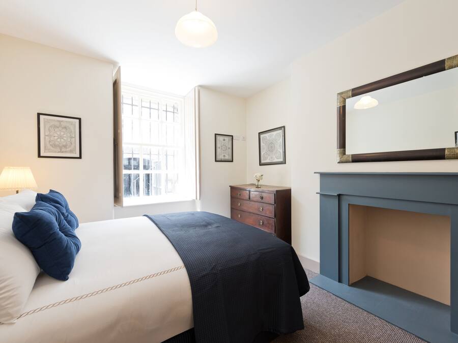 Quarto de hotel com cama, cômoda e lareira.