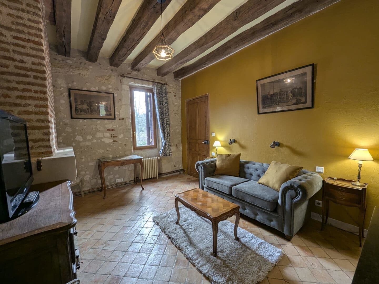 Una sala de estar acogedora con vigas de madera a la vista, un sofá, una mesa de centro y un televisor.