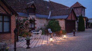 Un edificio tradicional con un patio a cuadros, asientos al aire libre y una zona iluminada por faroles.