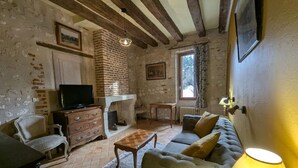 Una sala de estar rústica con paredes de ladrillo visto, una chimenea, un televisor, un sofá y una lámpara.