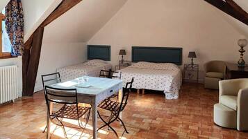 Un dormitorio tipo loft con vigas de madera a la vista, dos camas, una mesa de comedor y una silla.