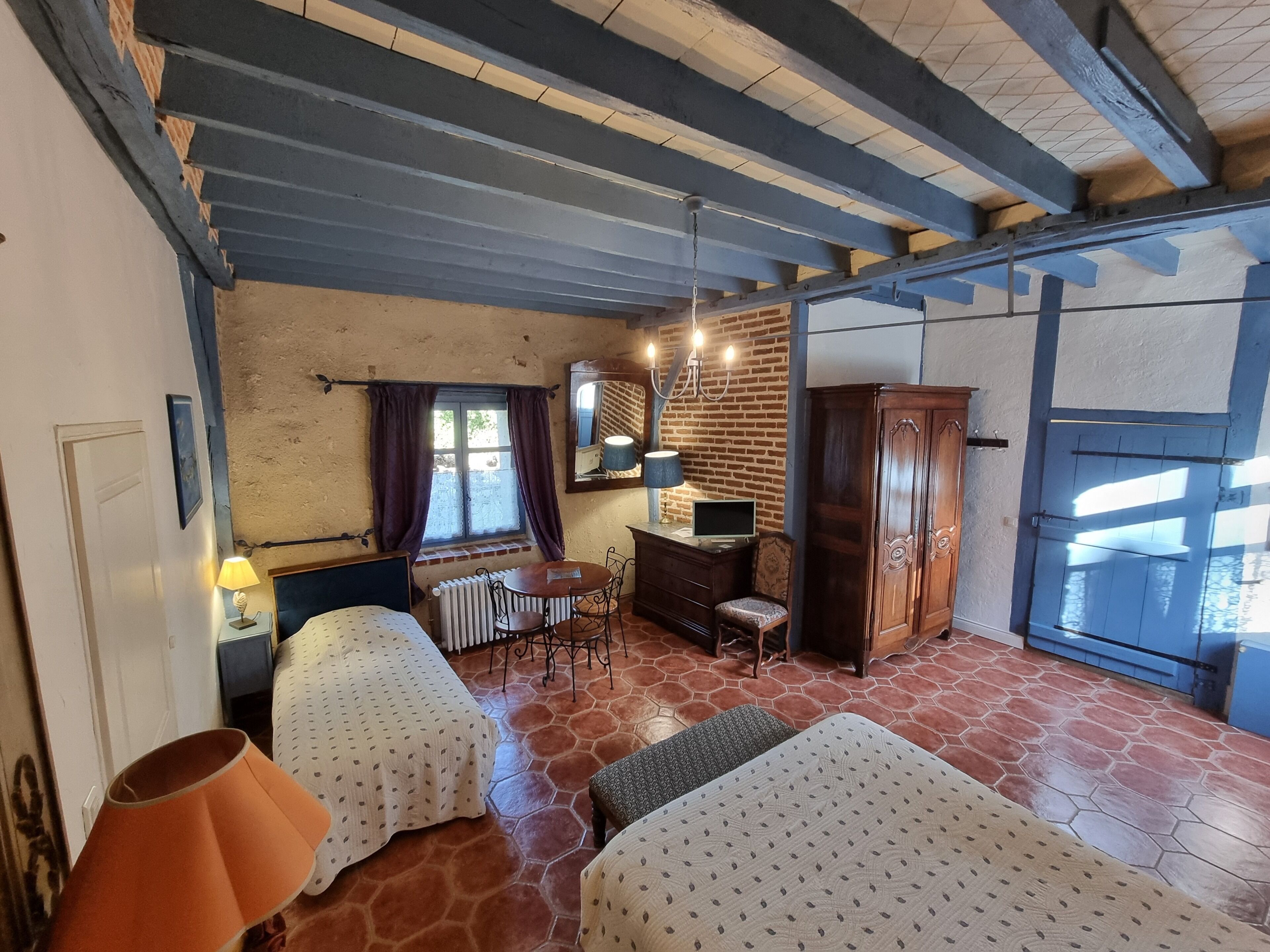 Een kamer met twee bedden, een bureau, een stoel, een radiator, een kledingkast en een raam met gordijnen.