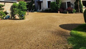 Una casa grande de varios pisos con camino de entrada de grava y un jardín bien cuidado.