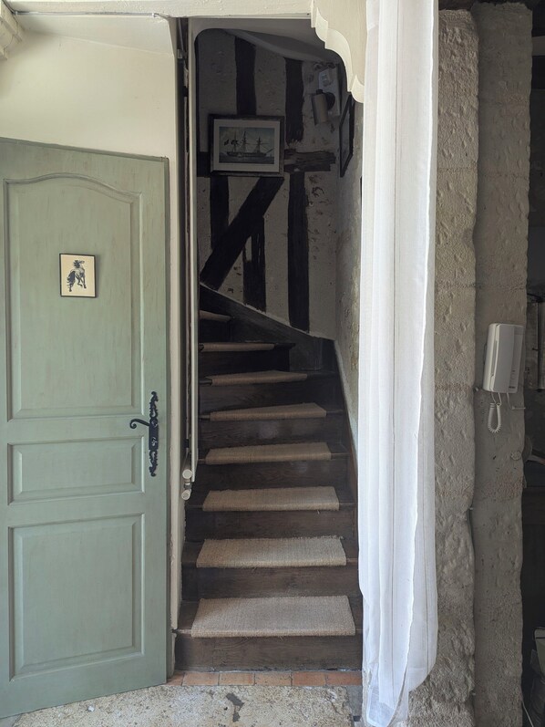 A staircase with a green door, a framed picture, and a phone on the wall.