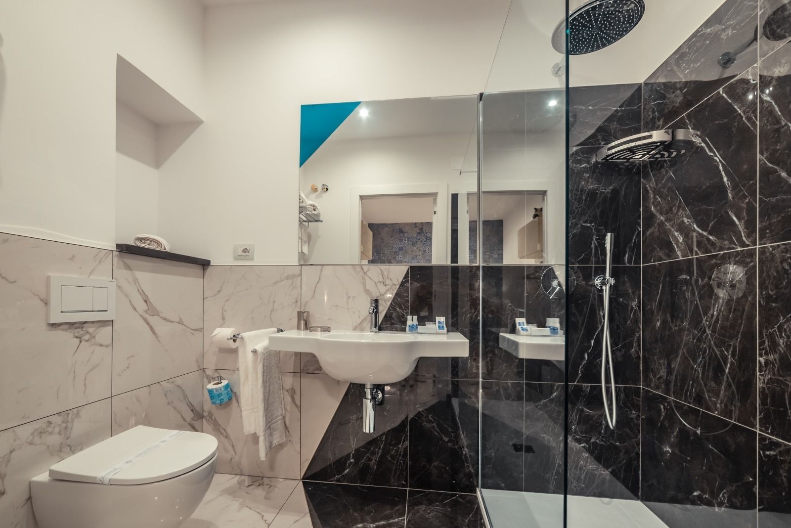 A modern bathroom with a marble sink, a toilet, and a shower area.
