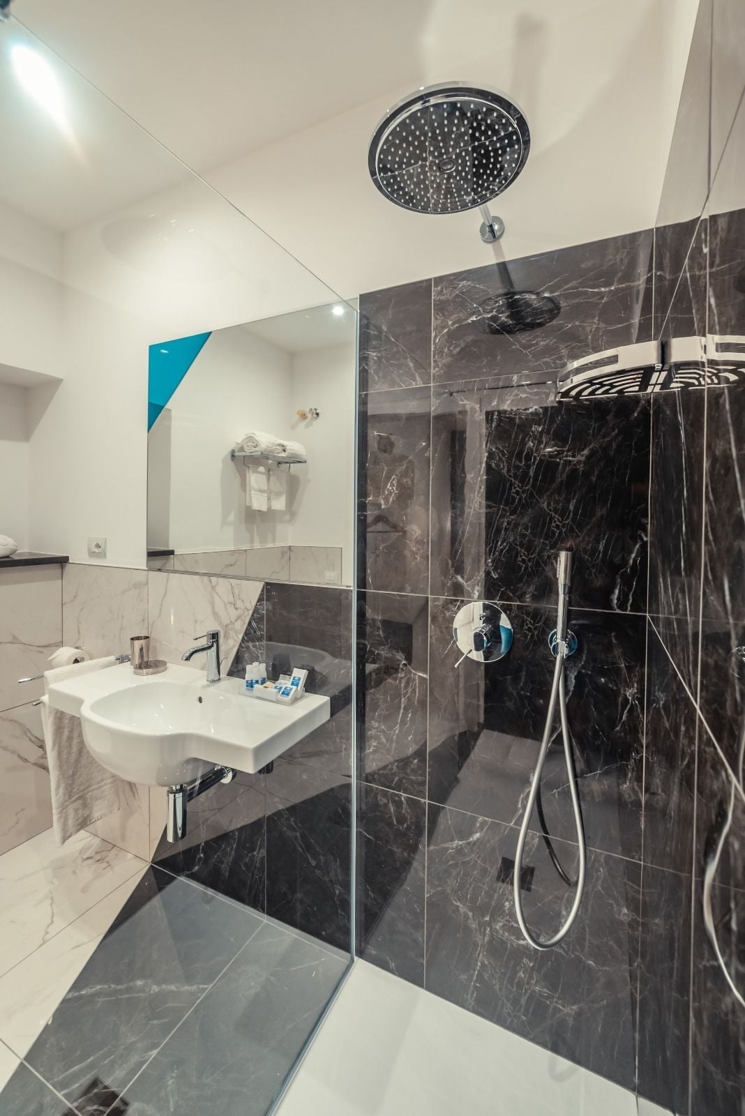 A modern bathroom with a glass-enclosed shower, a sink with a mirror, and marble tiles.