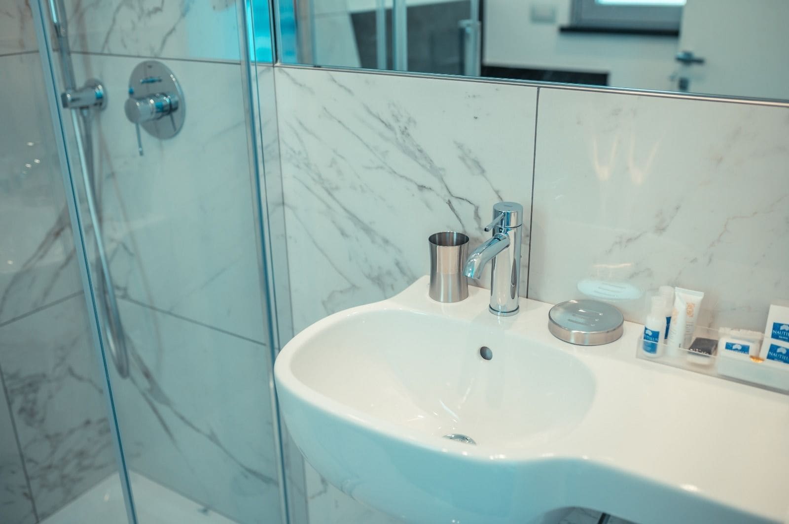 A bathroom with a white sink, a chrome faucet, and a glass shower enclosure.