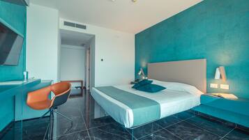 A modern hotel room with a bed, a desk, and a chair.