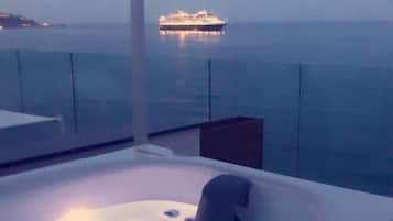 Uma banheira de hidromassagem com vista para o mar e uma ilha distante.
