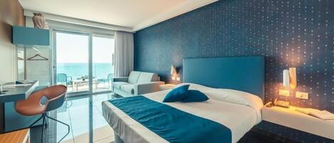 Habitación de hotel moderna con una cama grande, un escritorio y vistas al mar.