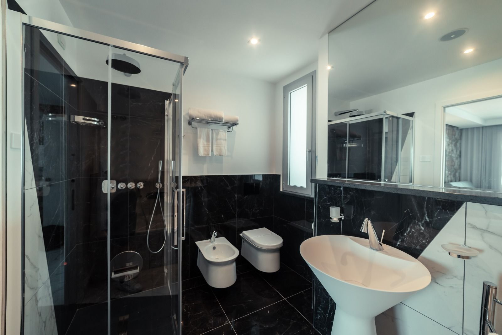 Un bany modern amb una dutxa envidrada amb vidre, un lavabo blanc i un vàter.