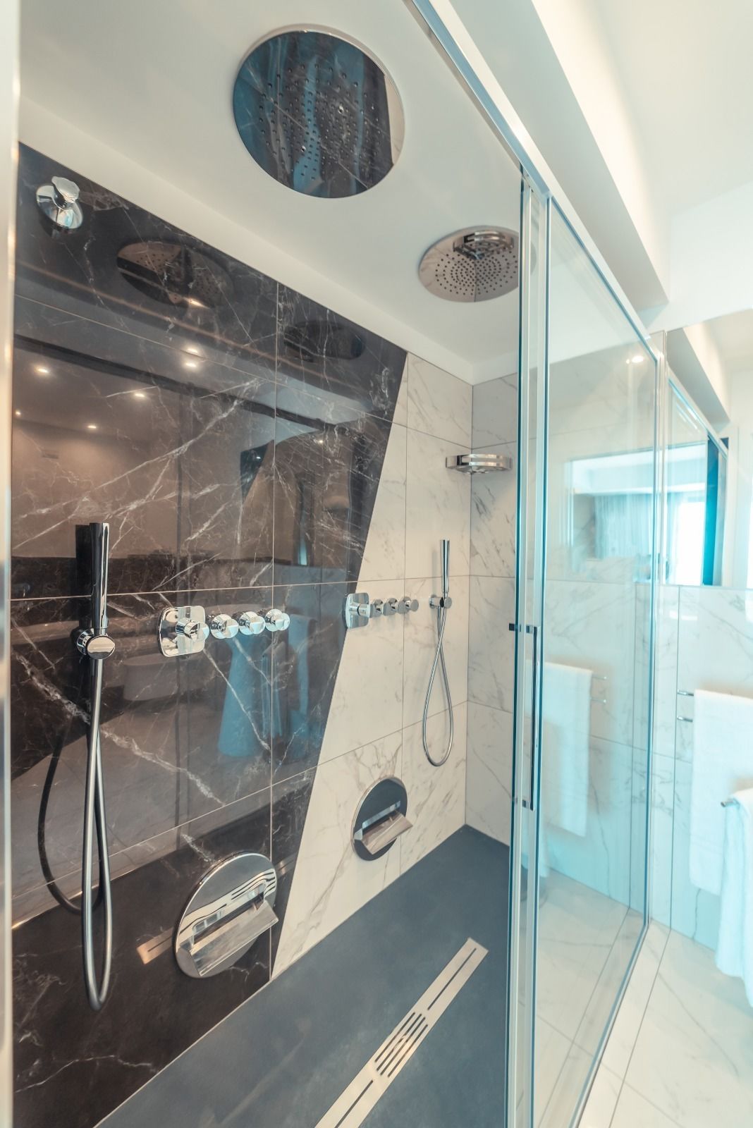 A modern bathroom with a glass-enclosed shower, marble walls, and a sleek design.