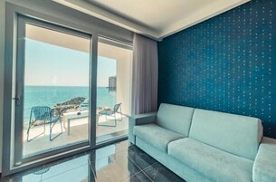 Una sala de estar moderna con un amplio ventanal corredero que da a un balcón con vista al mar.