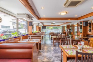 A restaurant with booths and tables, marble flooring, and potted plants. - Siam Palace Hotel (Bangkok)