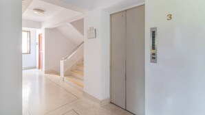 En lys, moderne gang med trappe, der fører op til en elevator mærket med nummer 3.