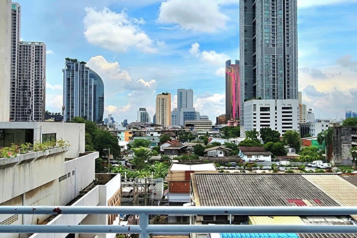 A cityscape with high-rise buildings, including a distinctive curved building and a tall skyscraper with pink and blue stripes.