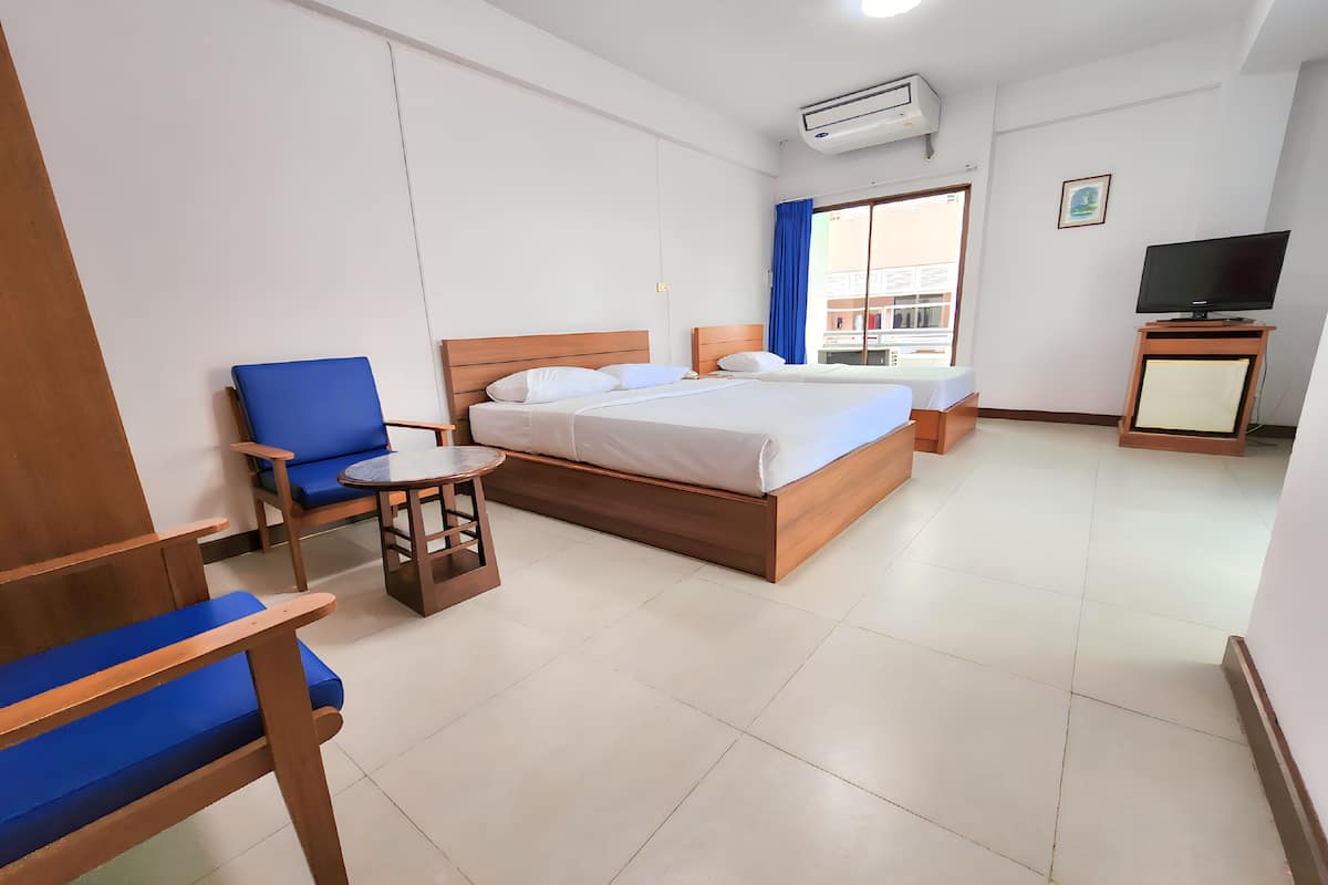 A hotel room with two beds, a TV, a small table, and a chair.